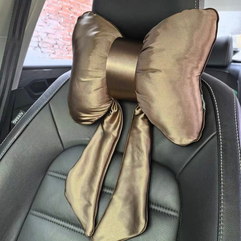 A luxurious golden brown satin bow-shaped car headrest pillow with elegant hanging streamers