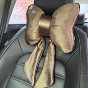 A luxurious golden brown satin bow-shaped car headrest pillow with elegant hanging streamers
