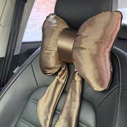 A luxurious golden brown satin bow-shaped car headrest pillow