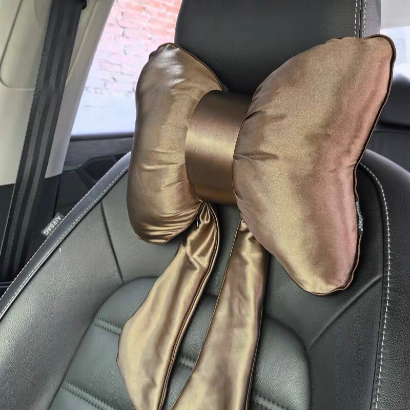 A luxurious golden brown satin bow-shaped car headrest pillow