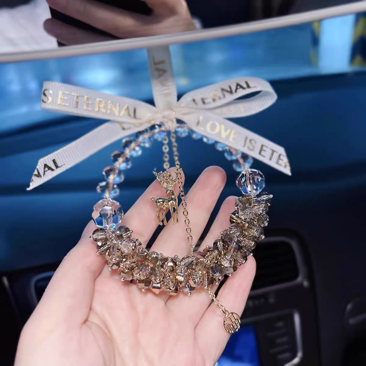 Decorative car hanging with 'Eternal Love is Eternally Love' ribbon held by a hand.