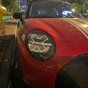 White X headlight decal sticker applied to Mini Cooper front headlights showing comic manga style effect