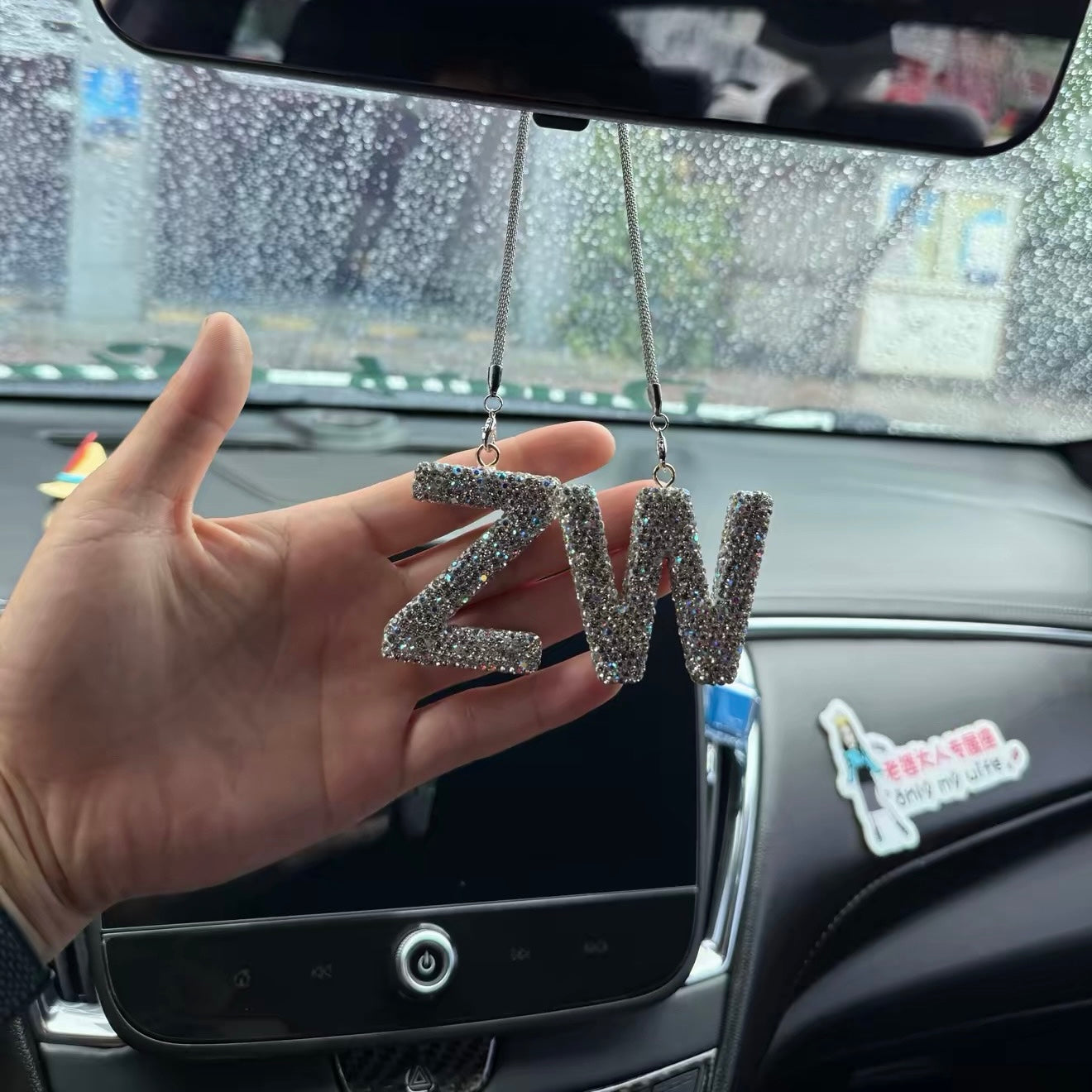 Rhinestone alphabet car pendant hanging from rearview mirror in SUV interior showing universal fit for all vehicles